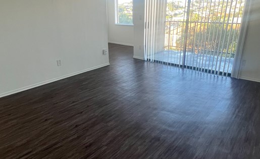 A room with wooden flooring and a window with blinds.