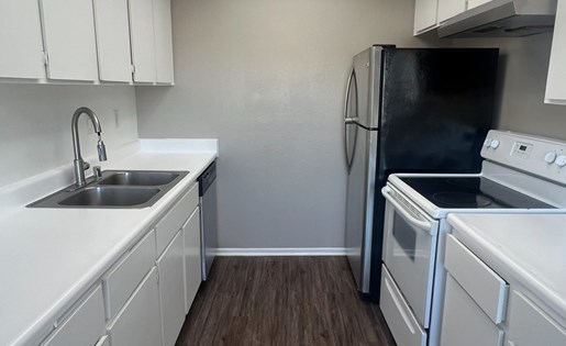 A kitchen with white cabinets and a black fridge.