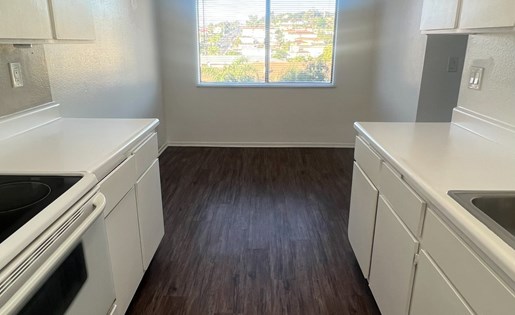 A kitchen with white cabinets and a wood floor.