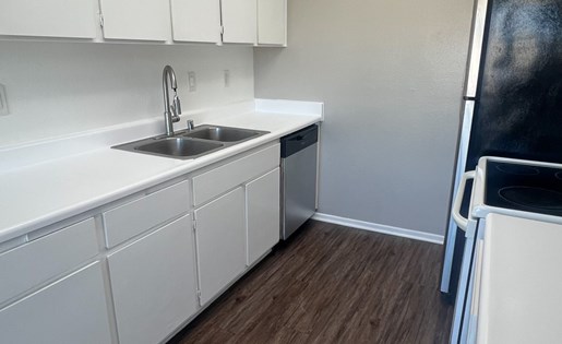 A kitchen with white cabinets and a wooden floor.