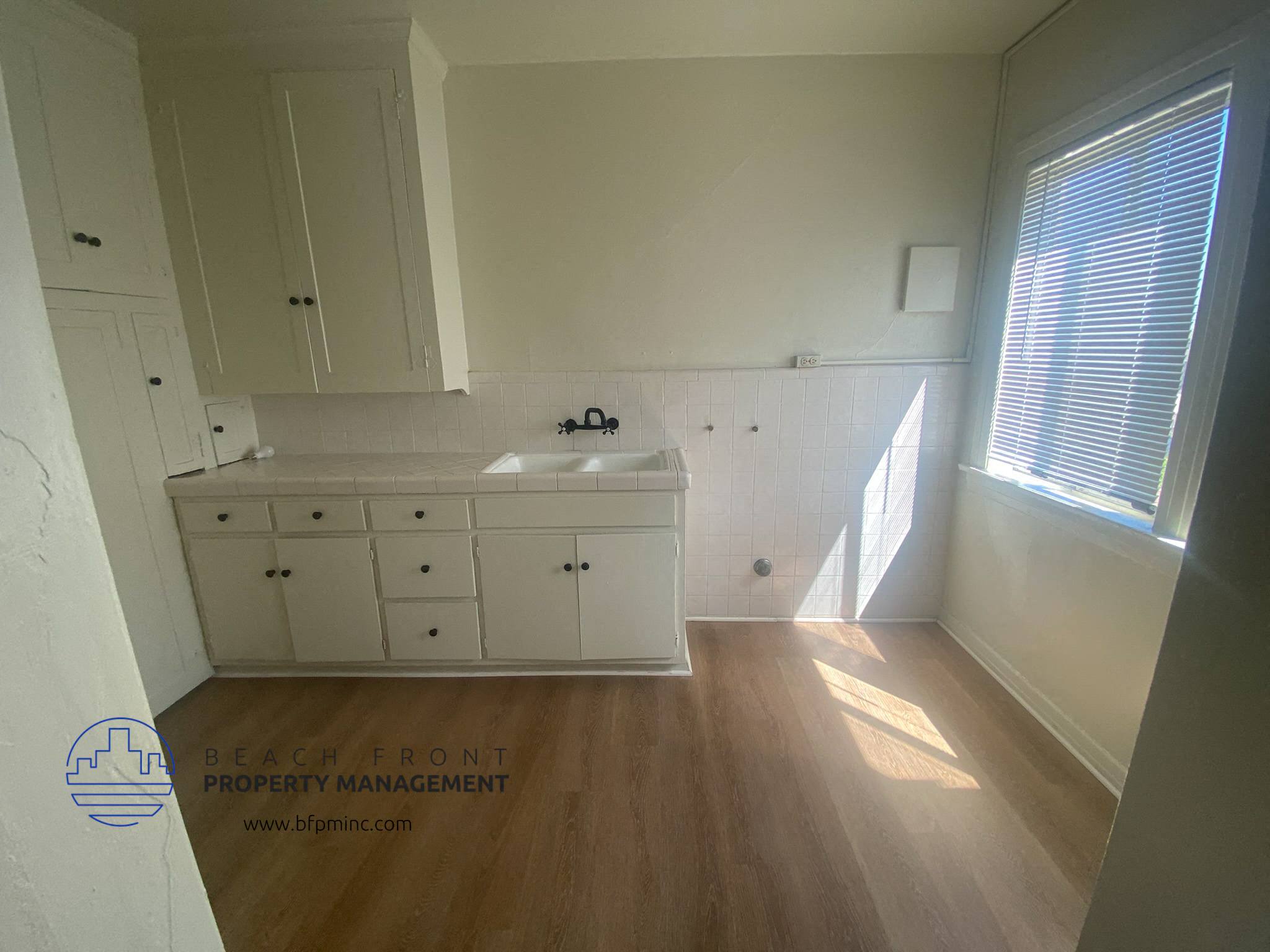 A kitchen with white cabinets and a wooden floor.