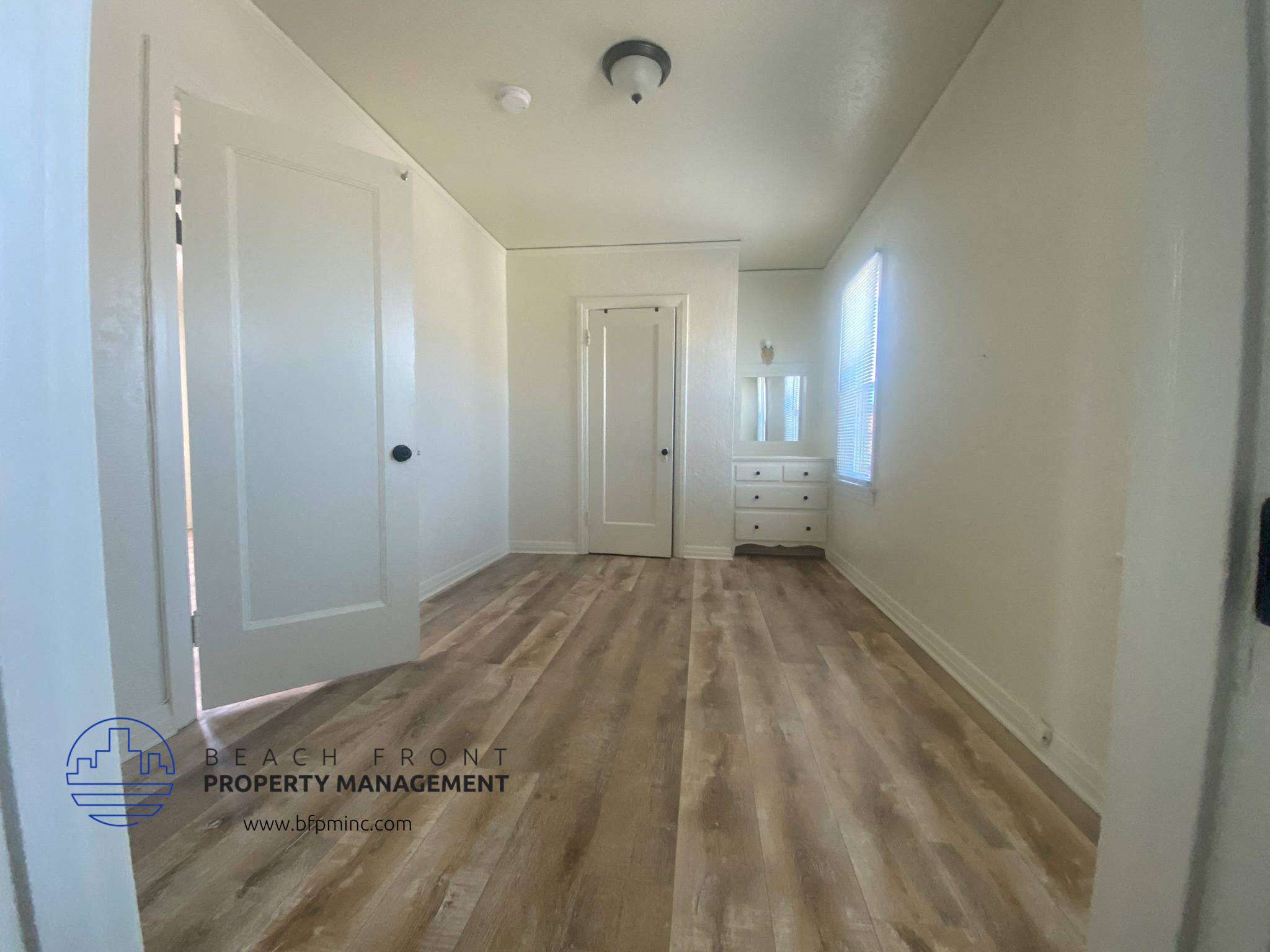 A hallway with wooden floors and white walls.