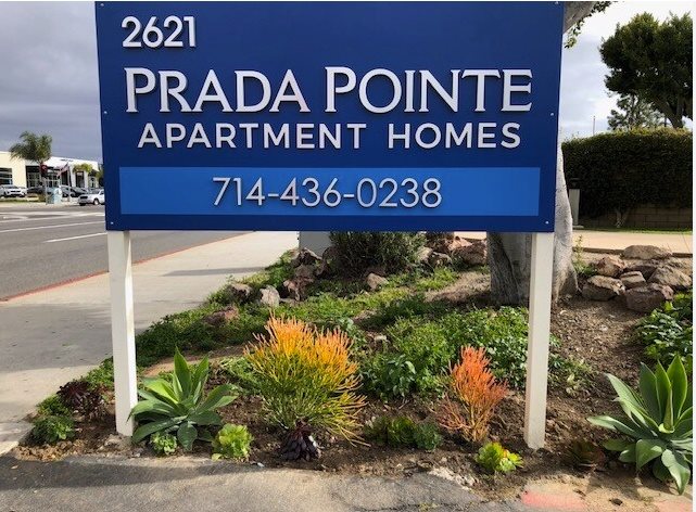 A blue sign for Prada Pointe Apartment Homes with a phone number on it.