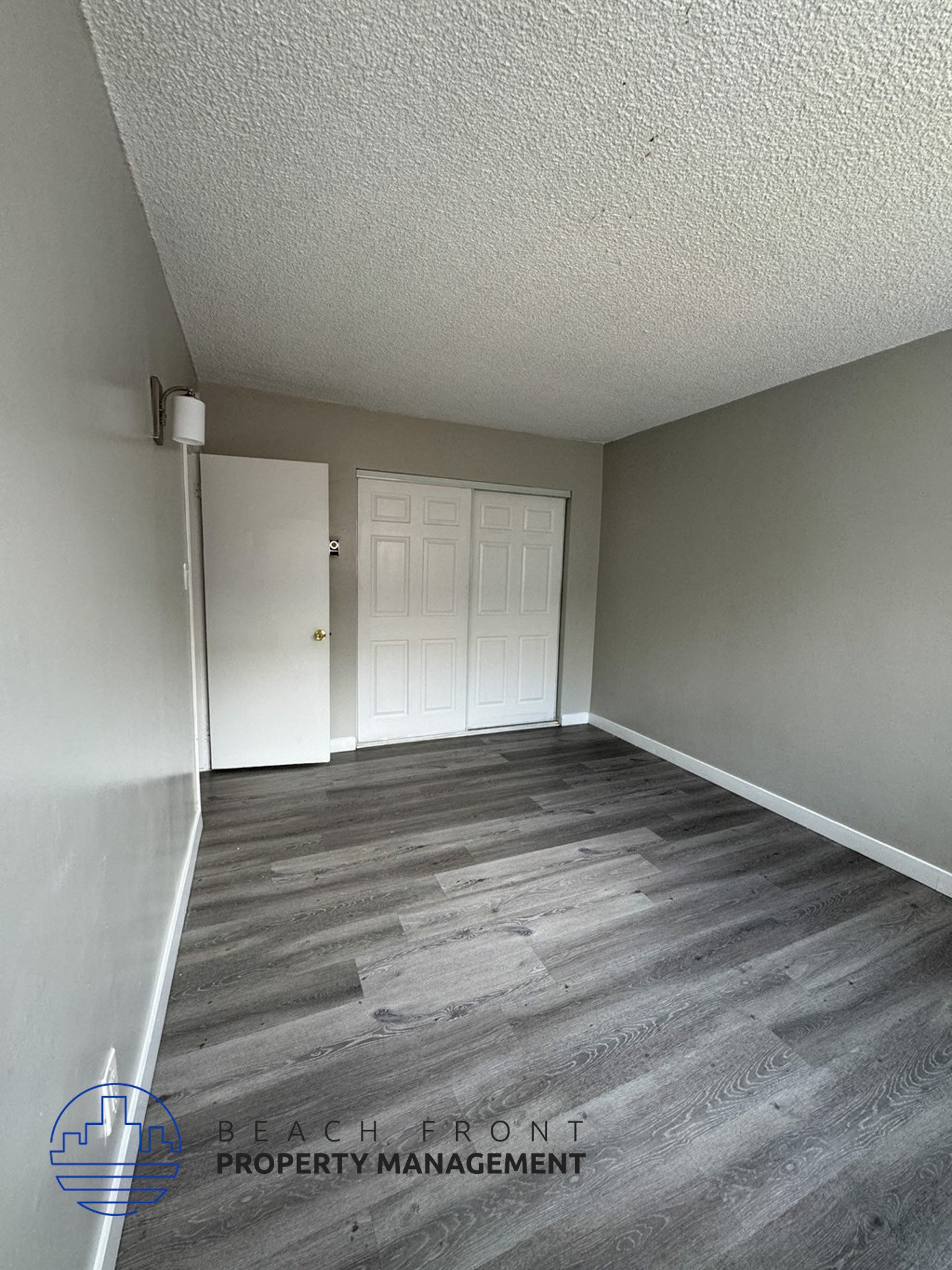 a empty room with a white door and wood flooring