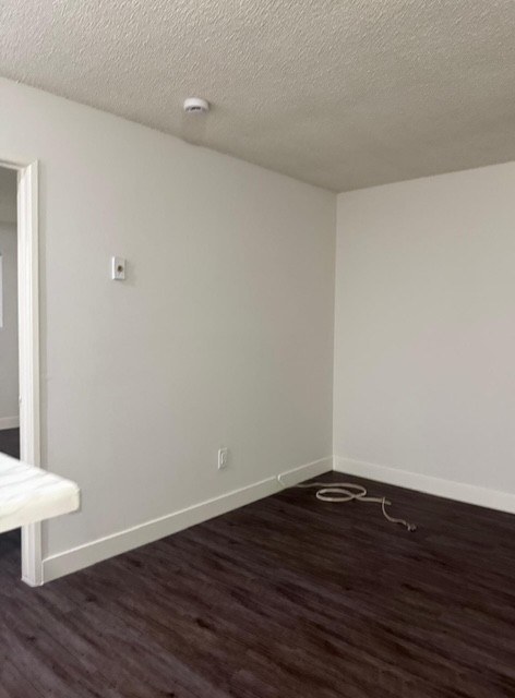 A room with a white wall and a brown floor.