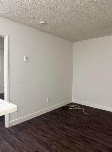 A room with a white wall and a brown floor.