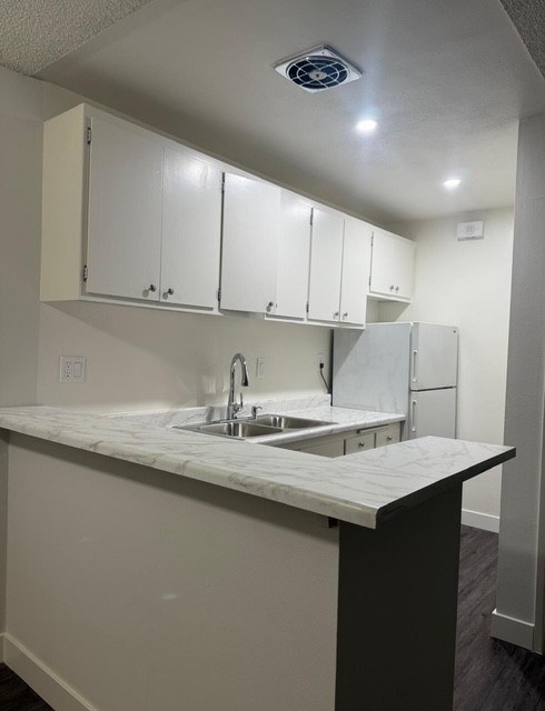 A kitchen with white cabinets and a marble countertop.