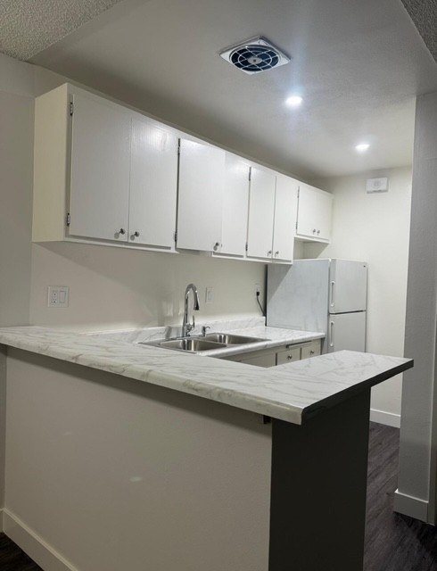 A kitchen with white cabinets and a marble countertop.
