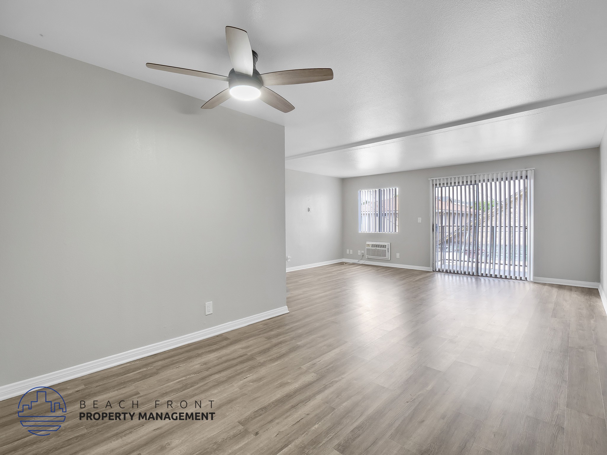 A spacious room with a ceiling fan and wooden flooring.