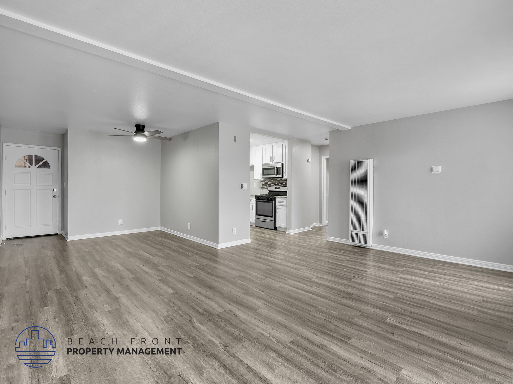 A spacious room with wooden flooring and a ceiling fan.