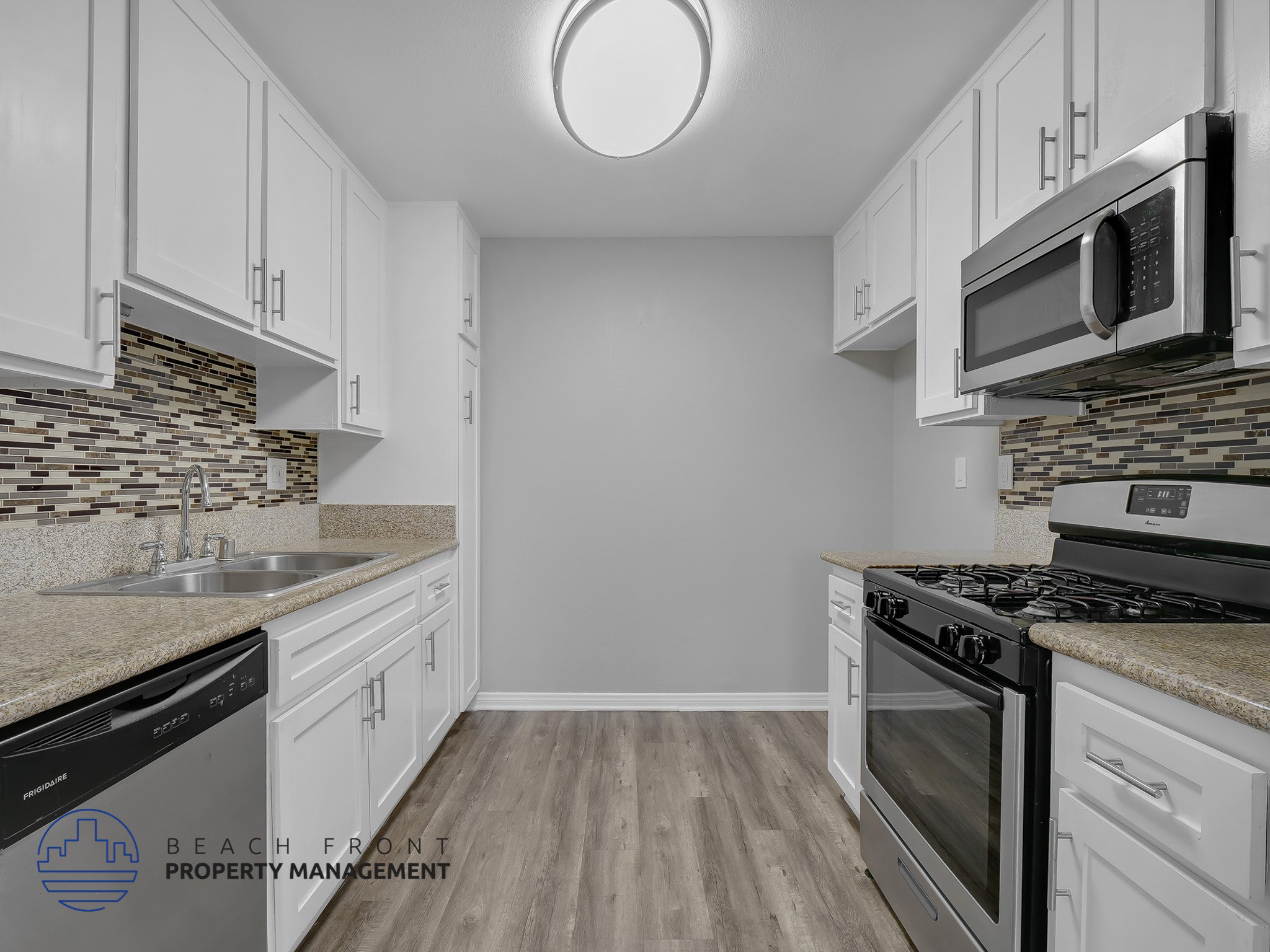 A kitchen with white cabinets and a stone backsplash.