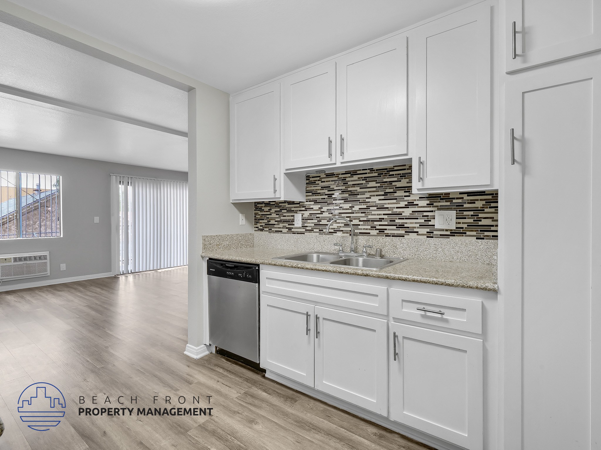 A kitchen with white cabinets and a stone backsplash.