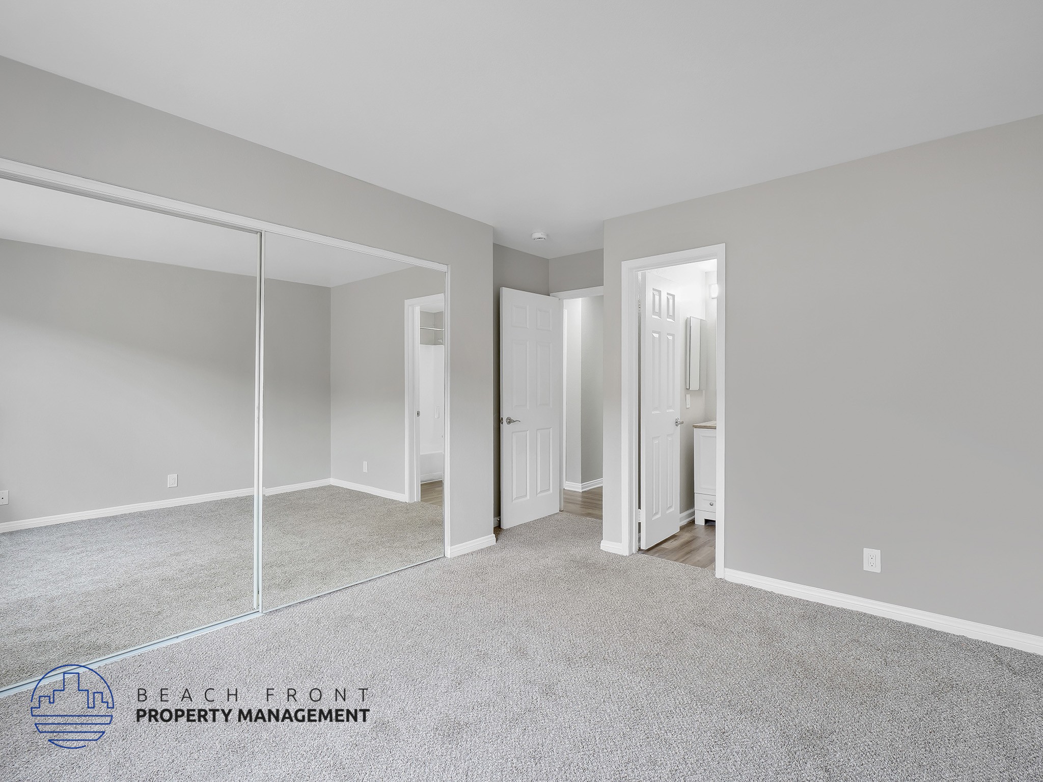 A spacious room with a carpeted floor and a mirror on the wall.
