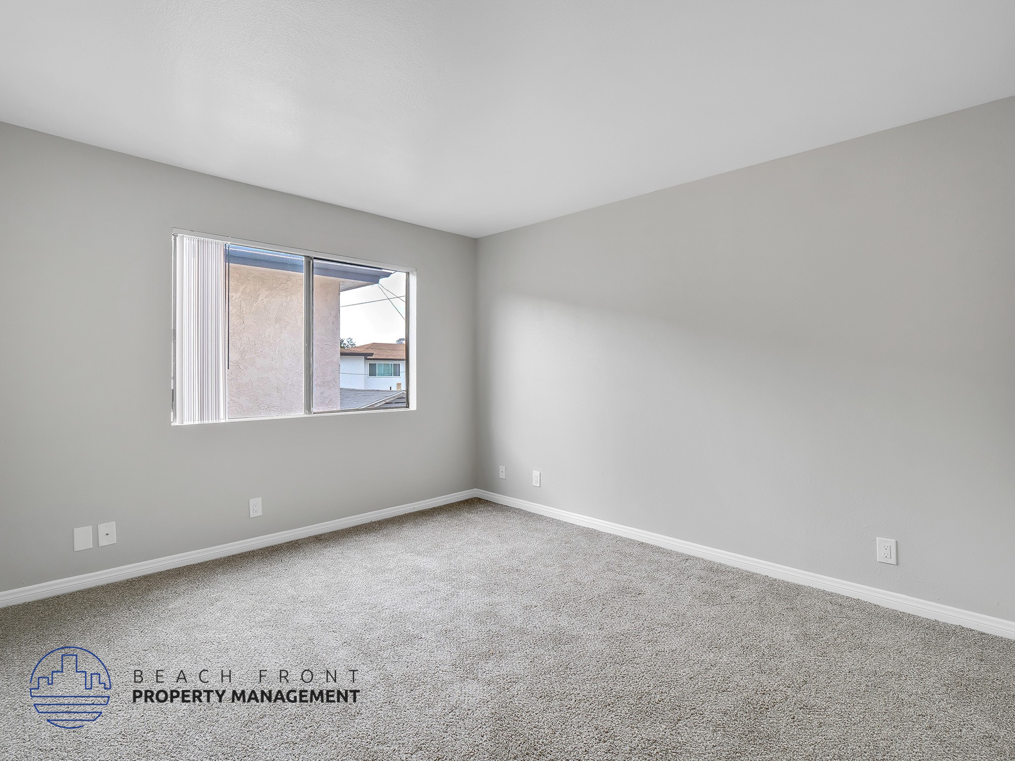 A room with a carpeted floor and a window showing a view of a building outside.