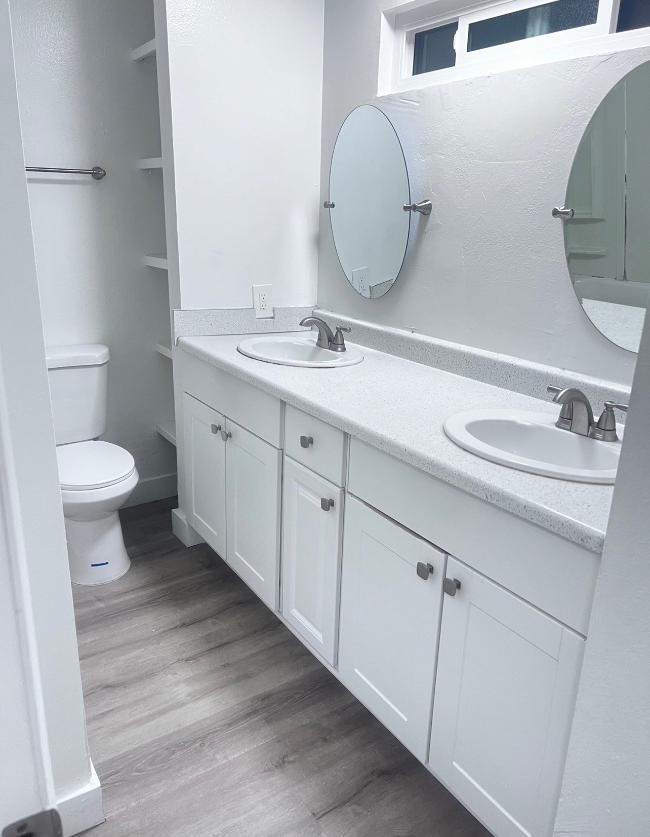 A white bathroom with a toilet, sink, and mirror.