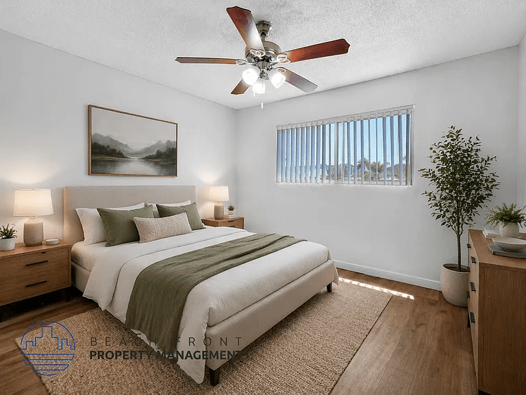 A bedroom with a bed, nightstands, a ceiling fan, and a painting on the wall.
