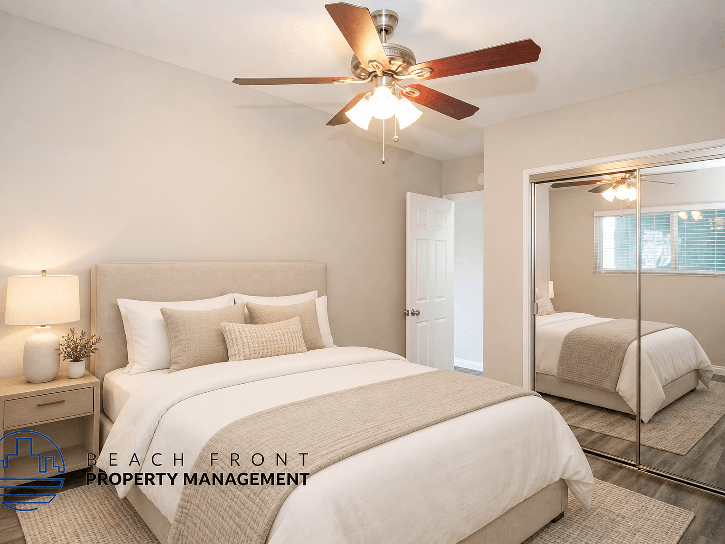 A bedroom with a bed, a ceiling fan, and a mirror.
