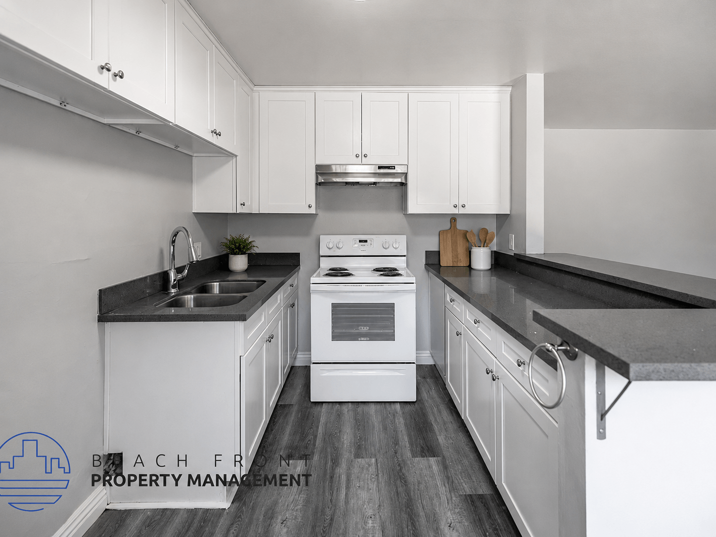 A modern kitchen with white cabinets and a black countertop.