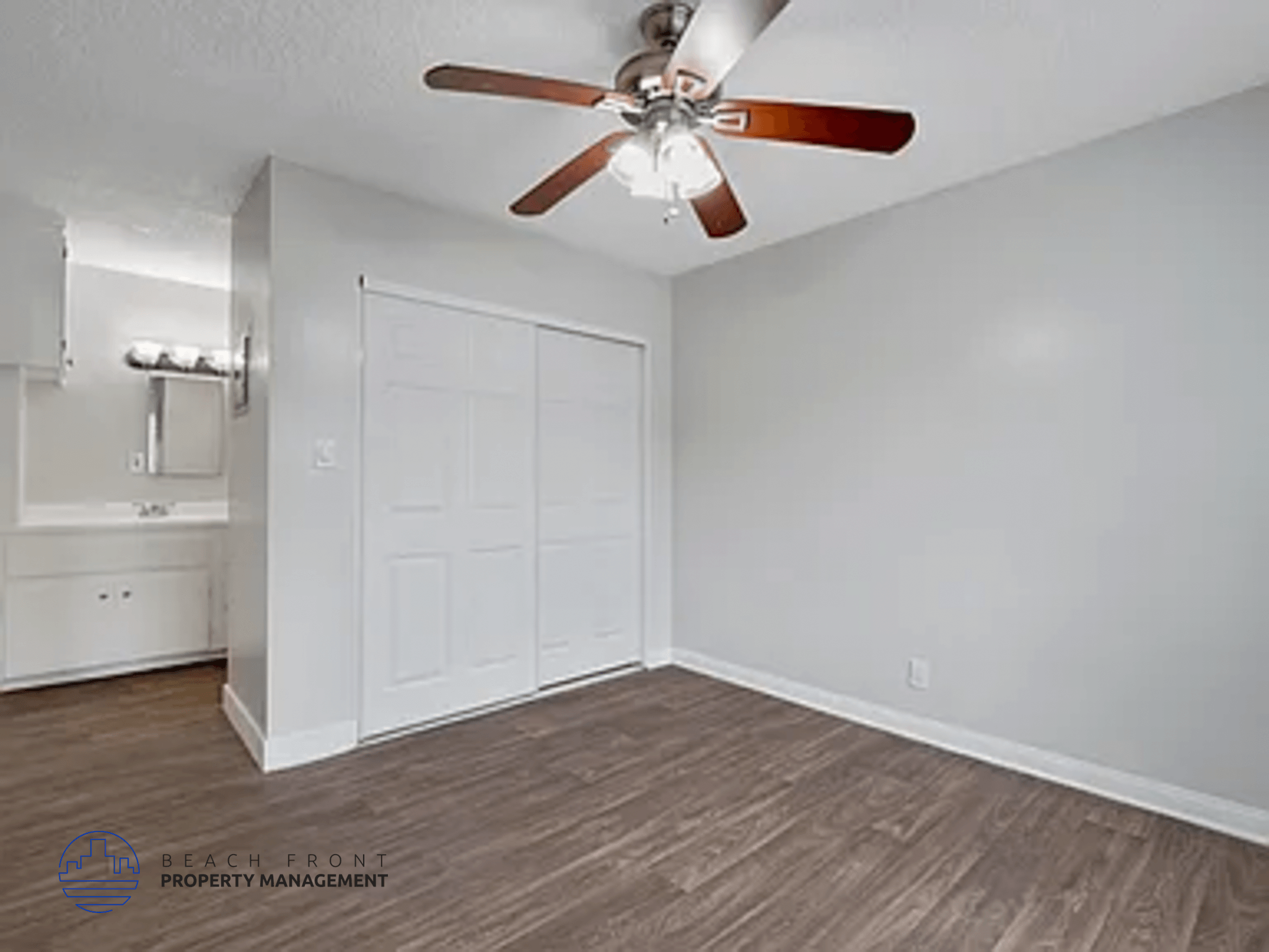 A room with a ceiling fan and a white door.