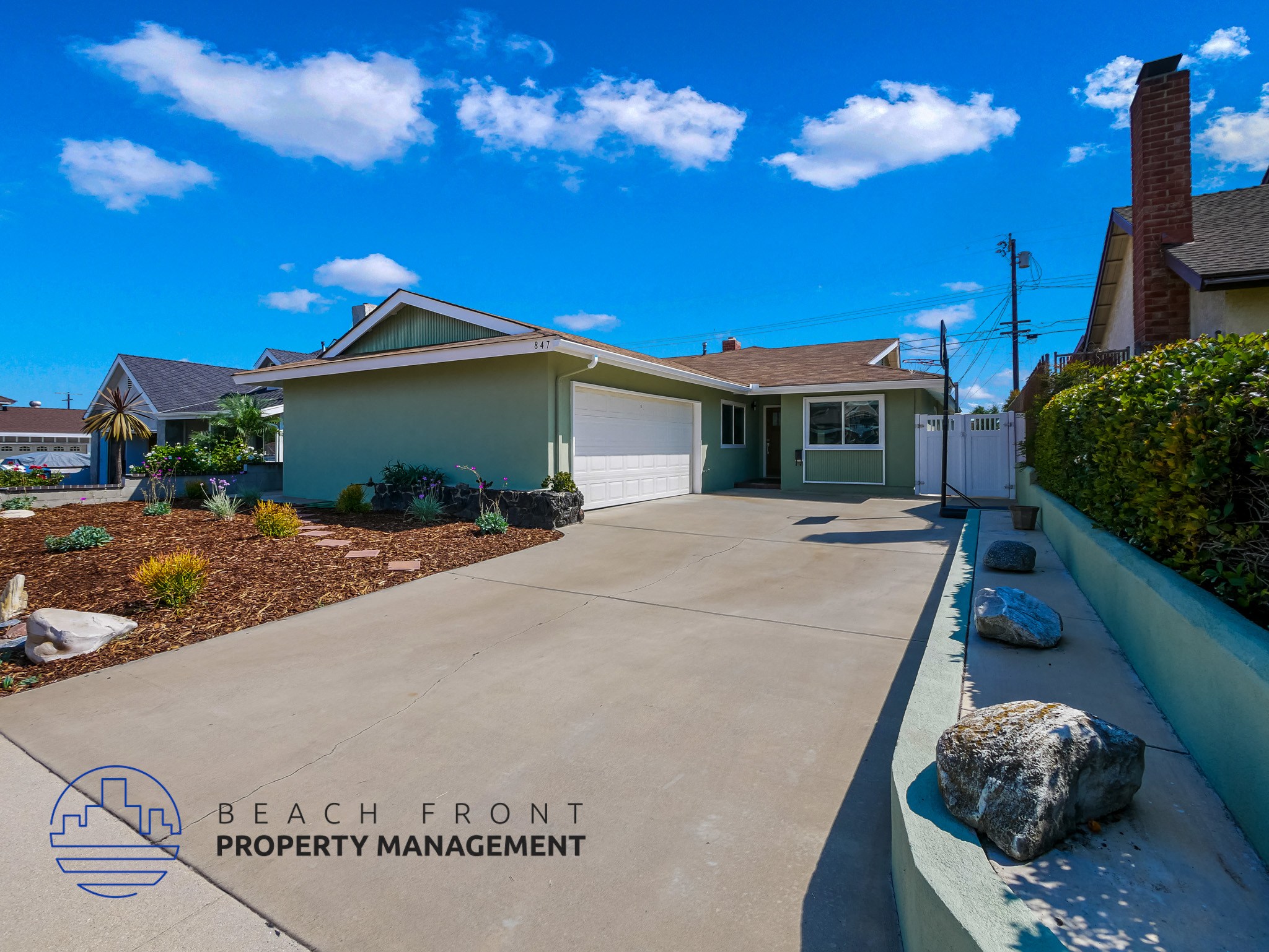 A house with a driveway and a logo for Beach Front Property Management.