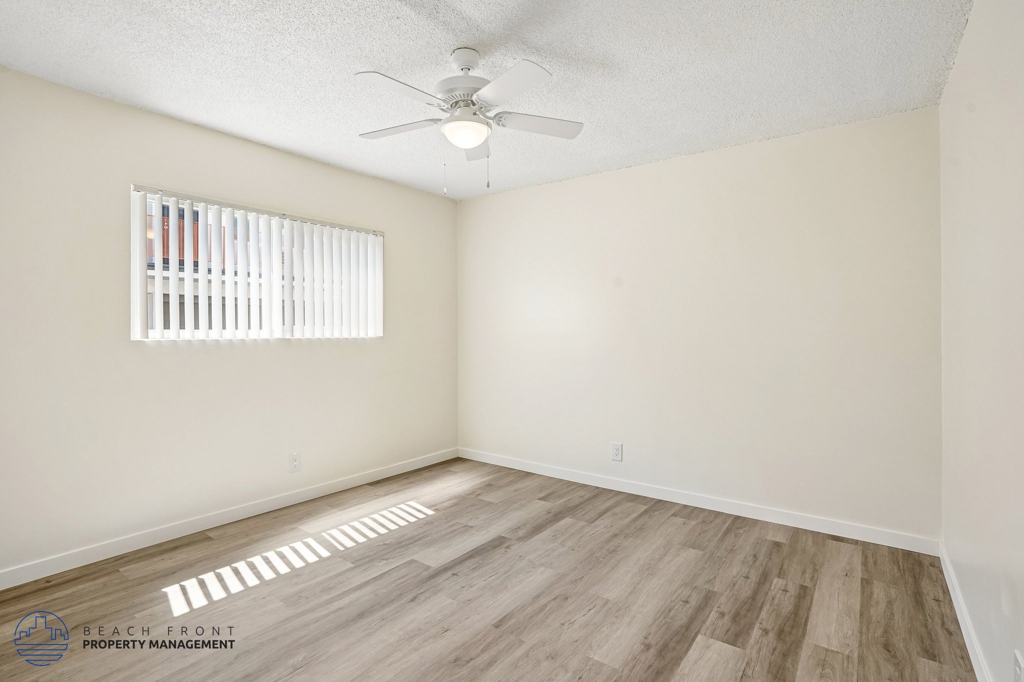 A room with a ceiling fan and a window with blinds.
