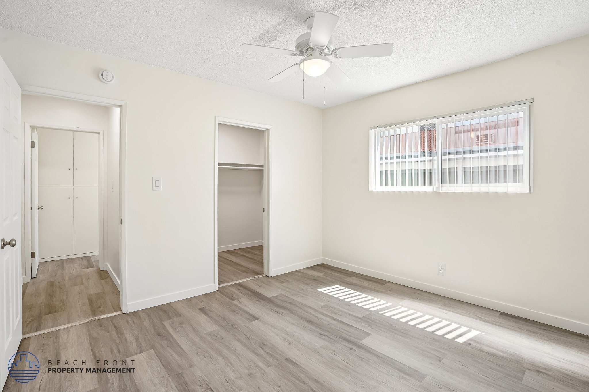 A room with a ceiling fan and a window with blinds.