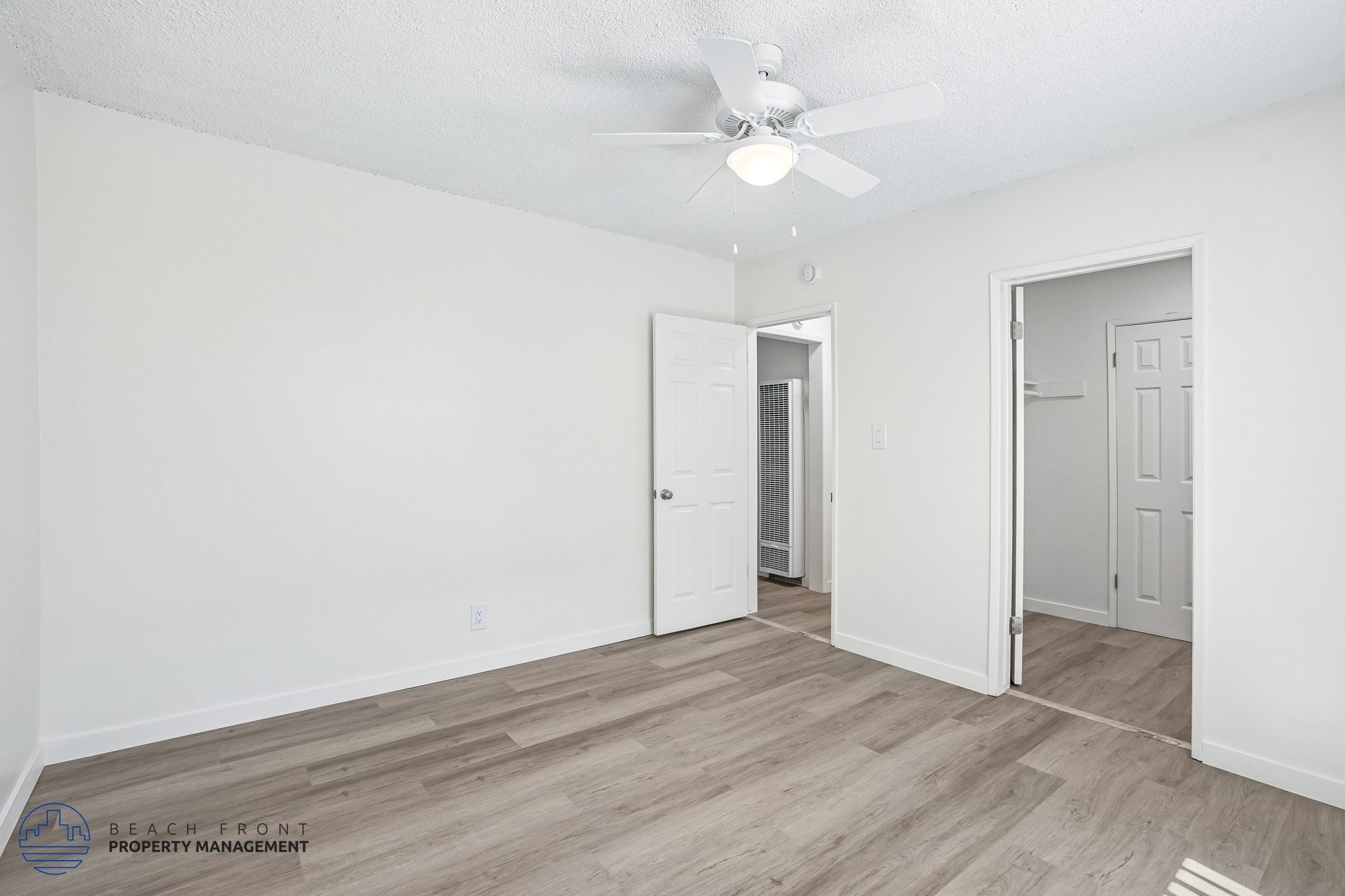 A spacious room with a ceiling fan and wooden flooring.