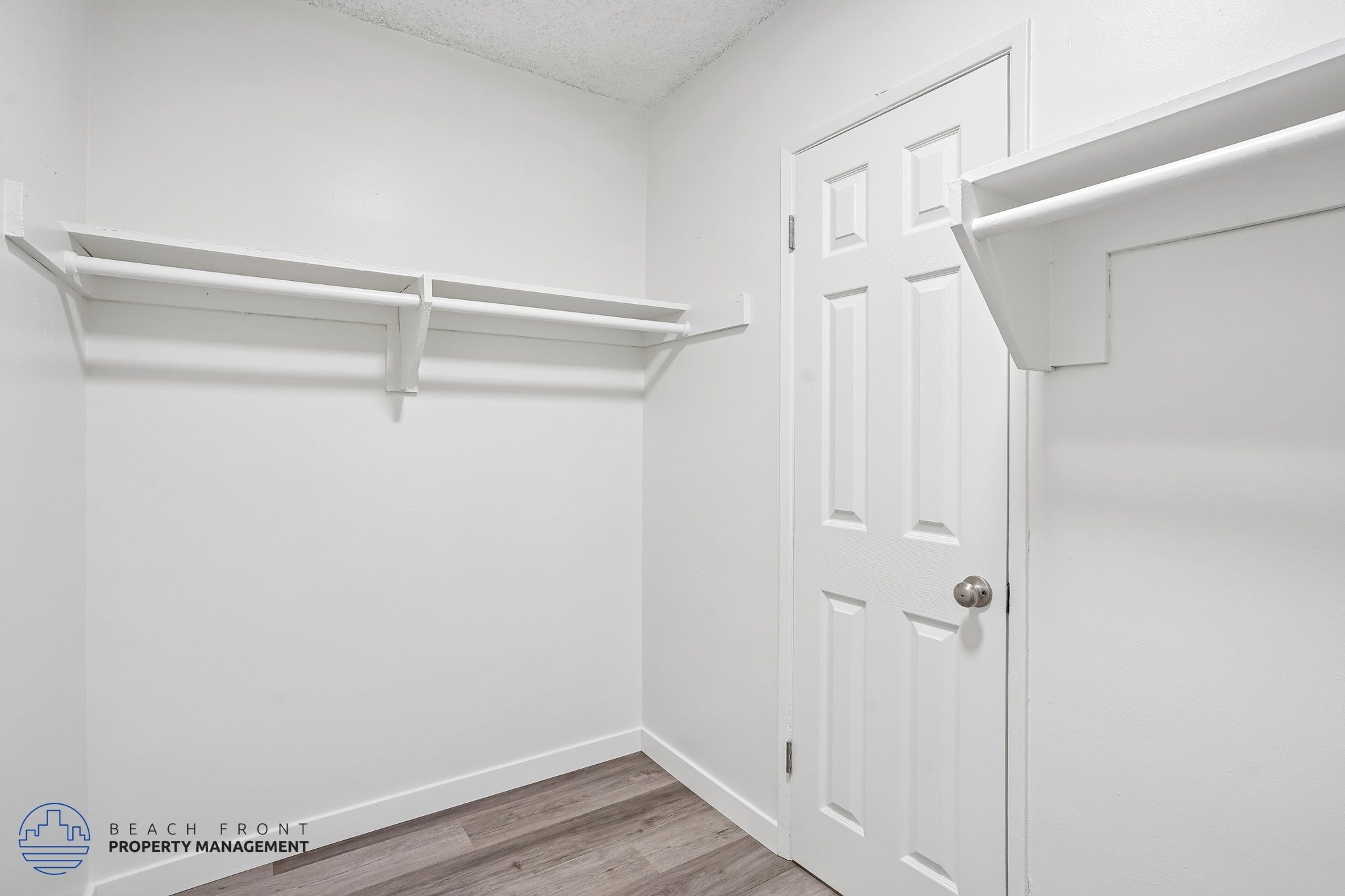 A white door is in a white room with a white shelf above it.