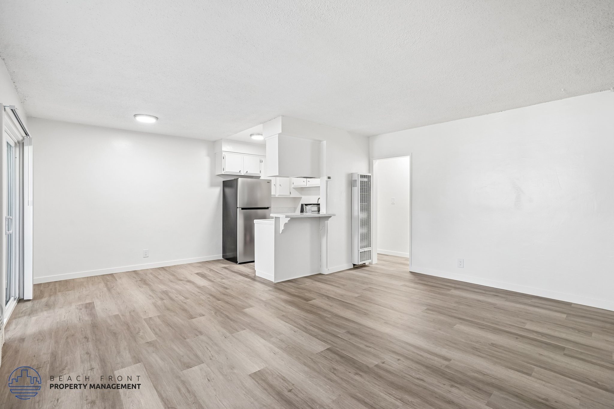 A spacious kitchen with white cabinets and a wooden floor.