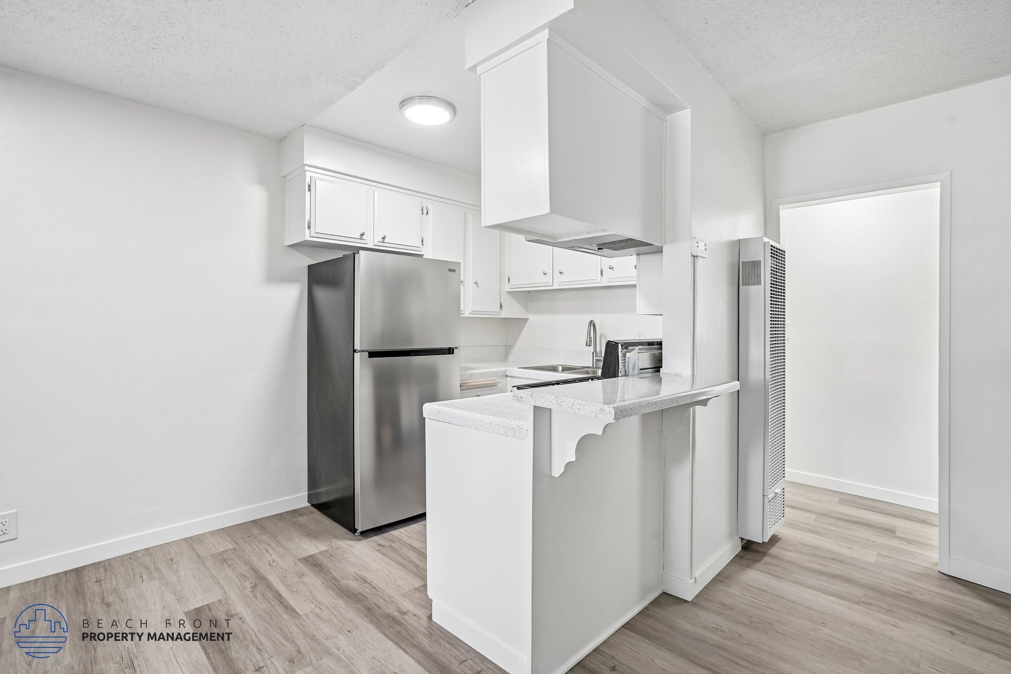 A kitchen with white cabinets and a stainless steel refrigerator.