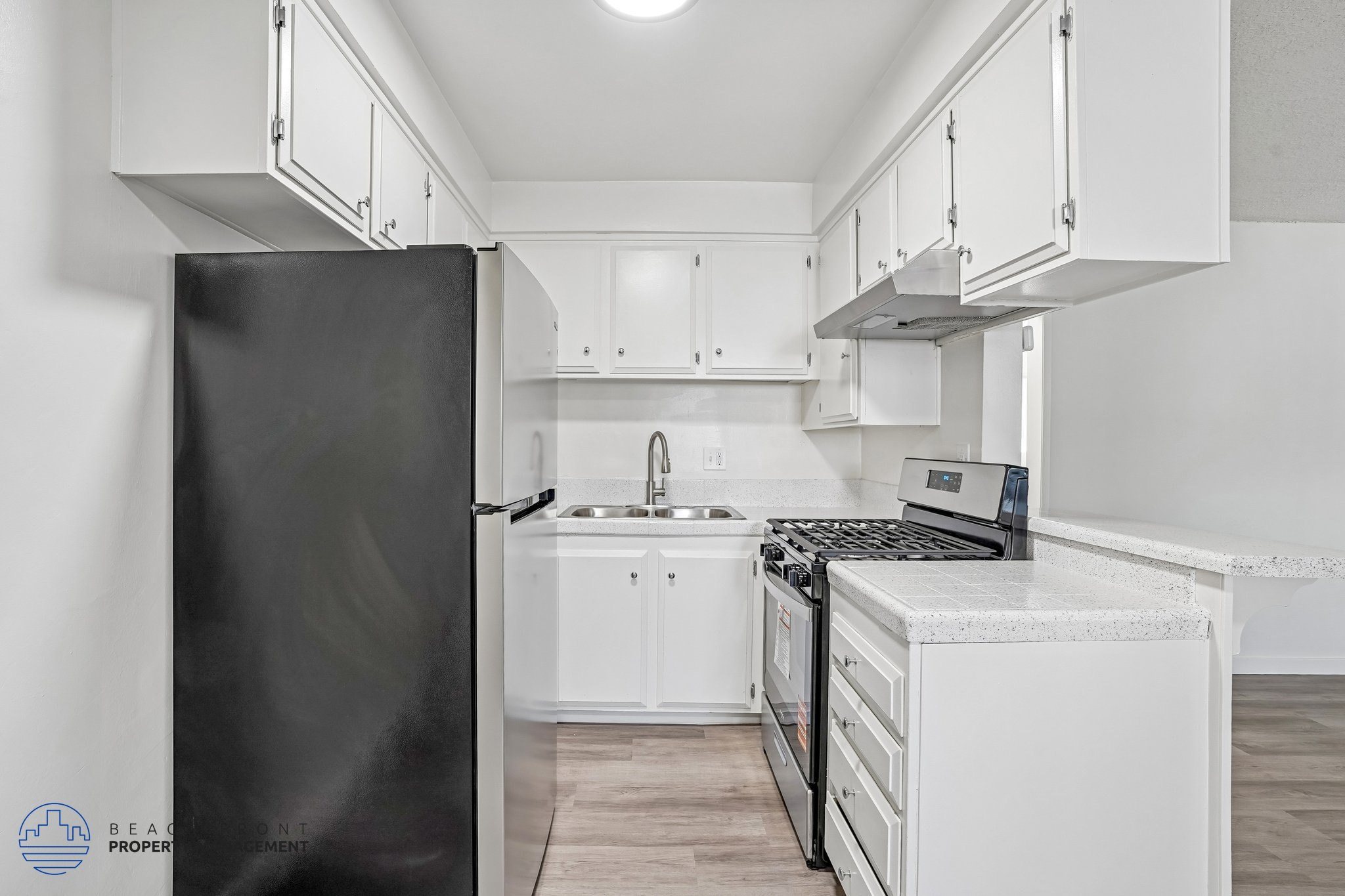 A kitchen with a black refrigerator and white cabinets.