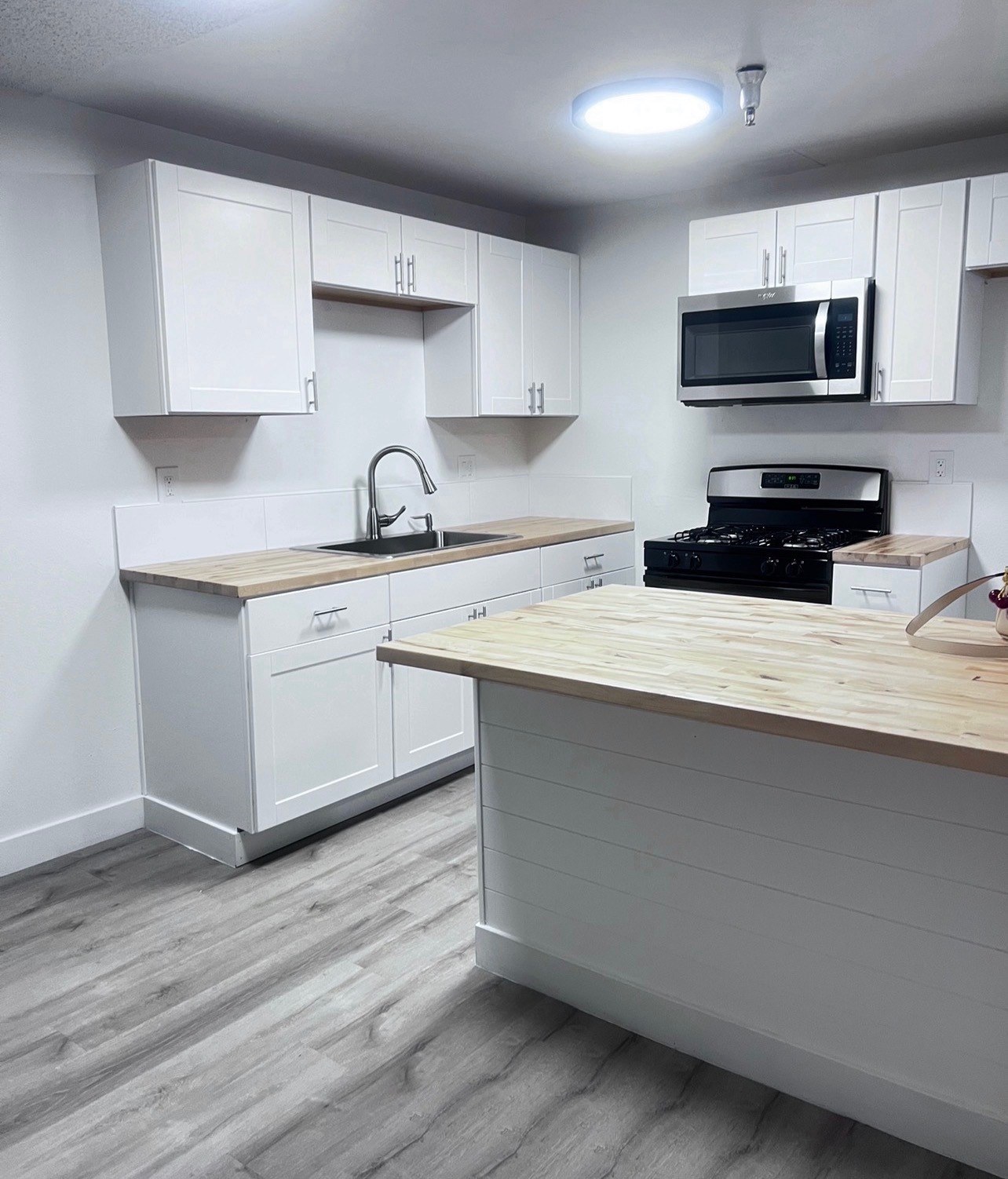 A kitchen with white cabinets and a wooden counter.