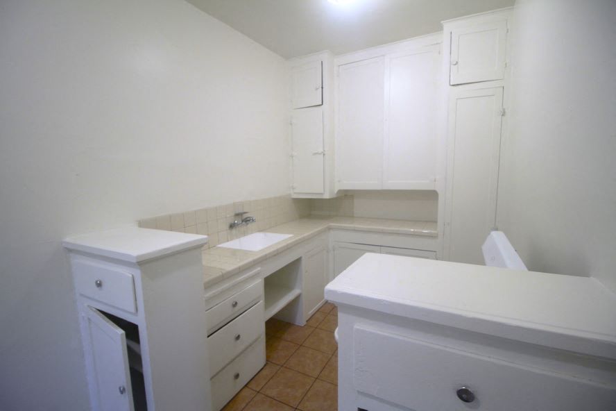 an empty kitchen with white cabinets and a sink