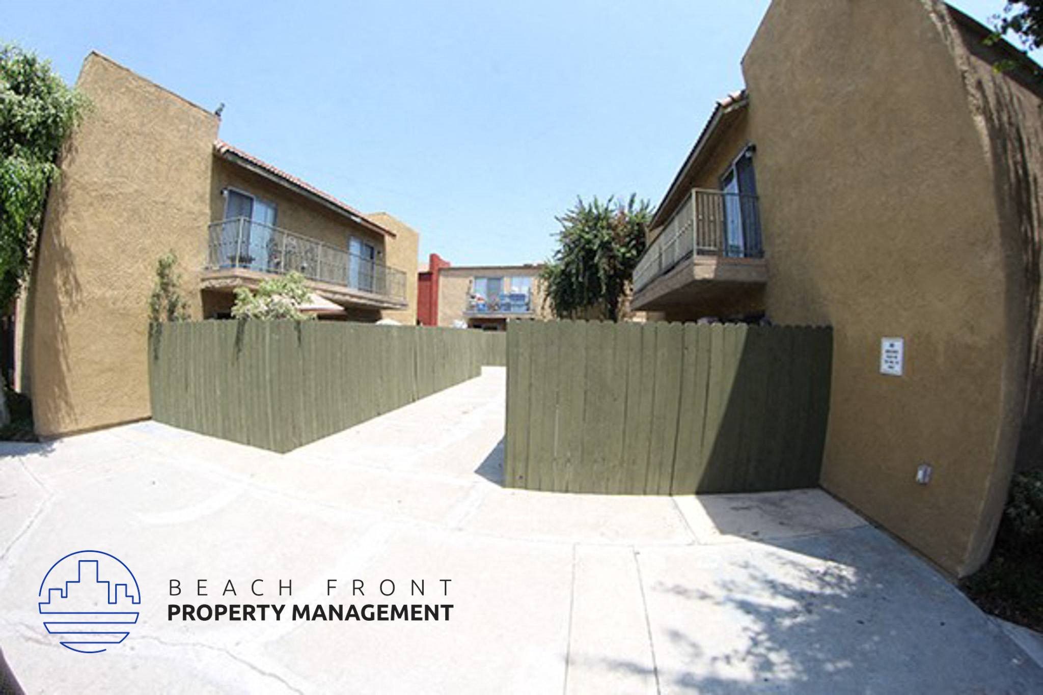 a fenced in driveway between two buildings with trees,a fenced in driveway between two buildings with trees