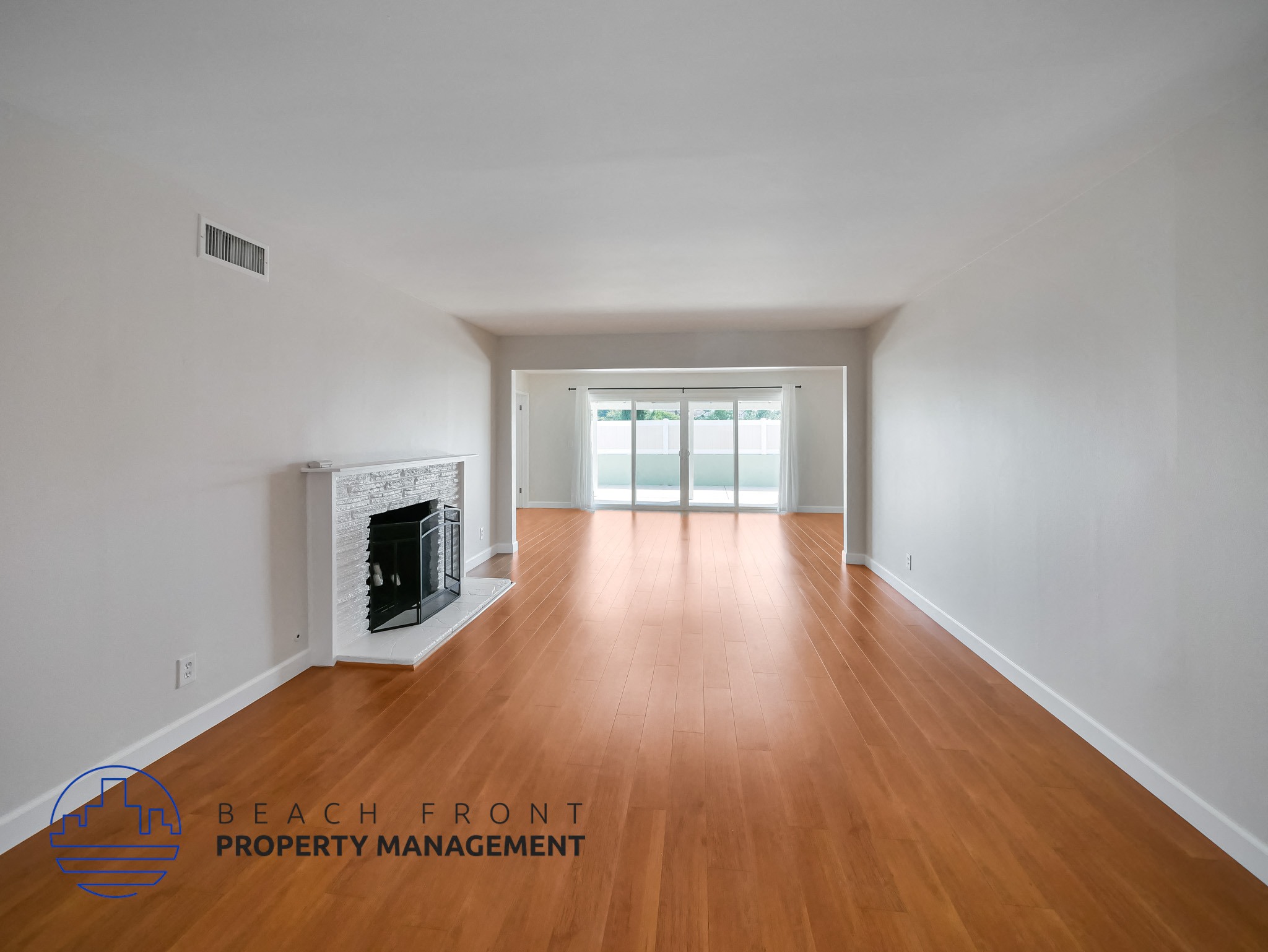A spacious room with wooden floors and a fireplace.