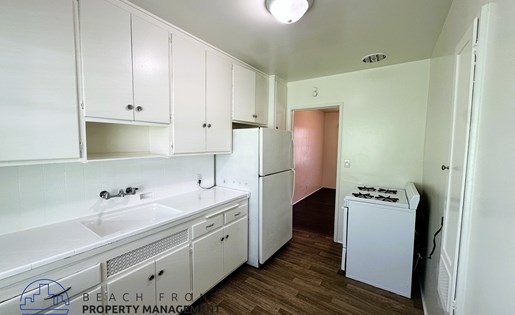 A kitchen with white cabinets and a white fridge.