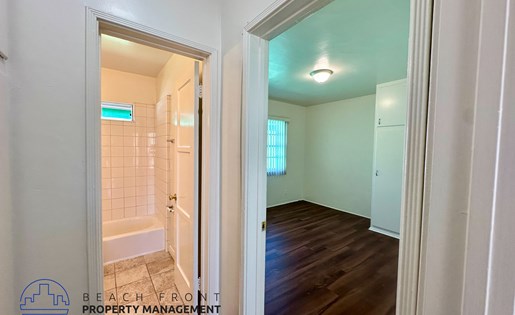 A hallway with a doorway leading to a bathroom with a tiled shower.
