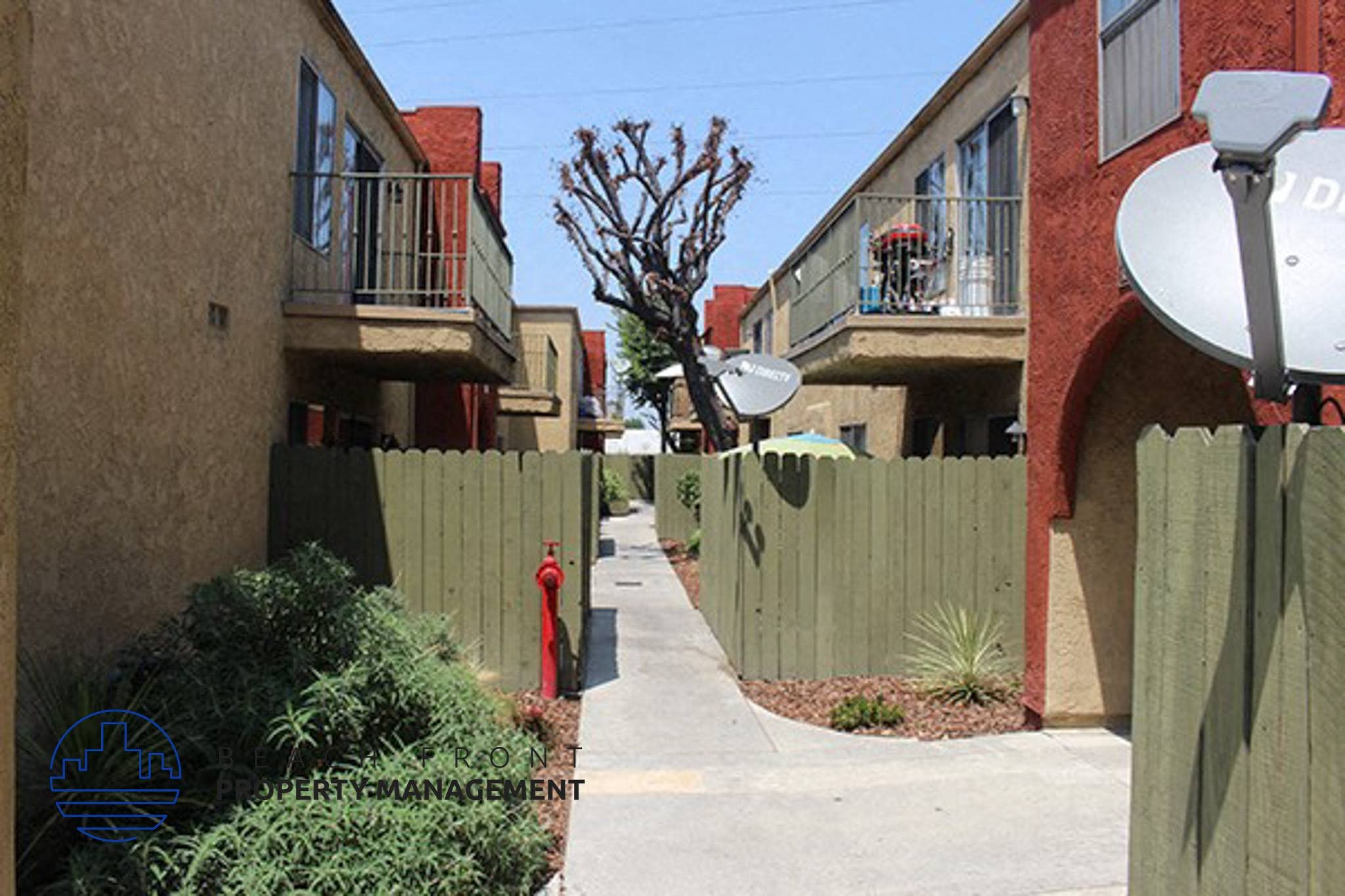 a sidewalk between two apartment buildings and a red fire hydrant,a sidewalk between two apartment buildings and a red fire hydrant