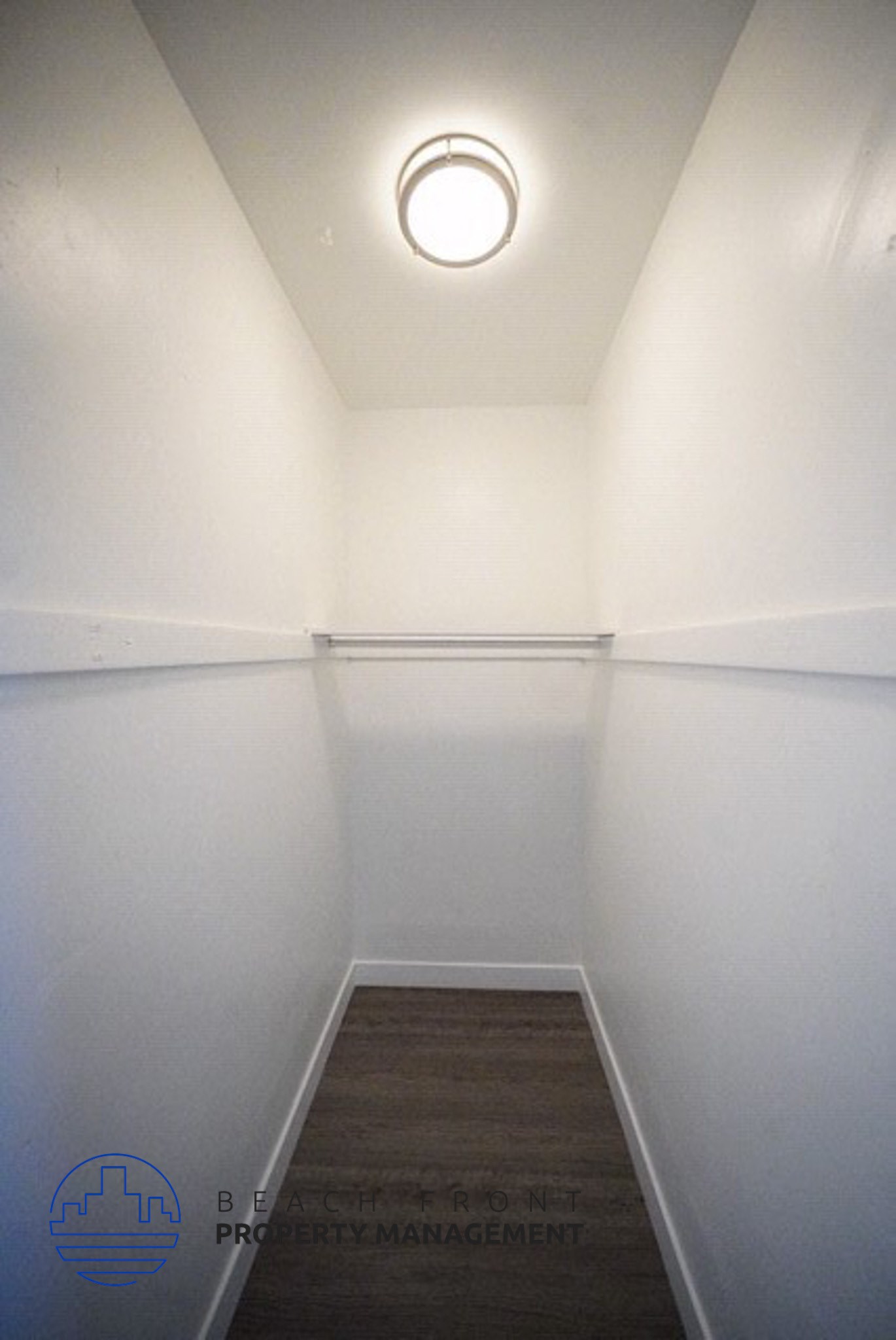 a small room with white walls and a wooden floor and a ceiling light