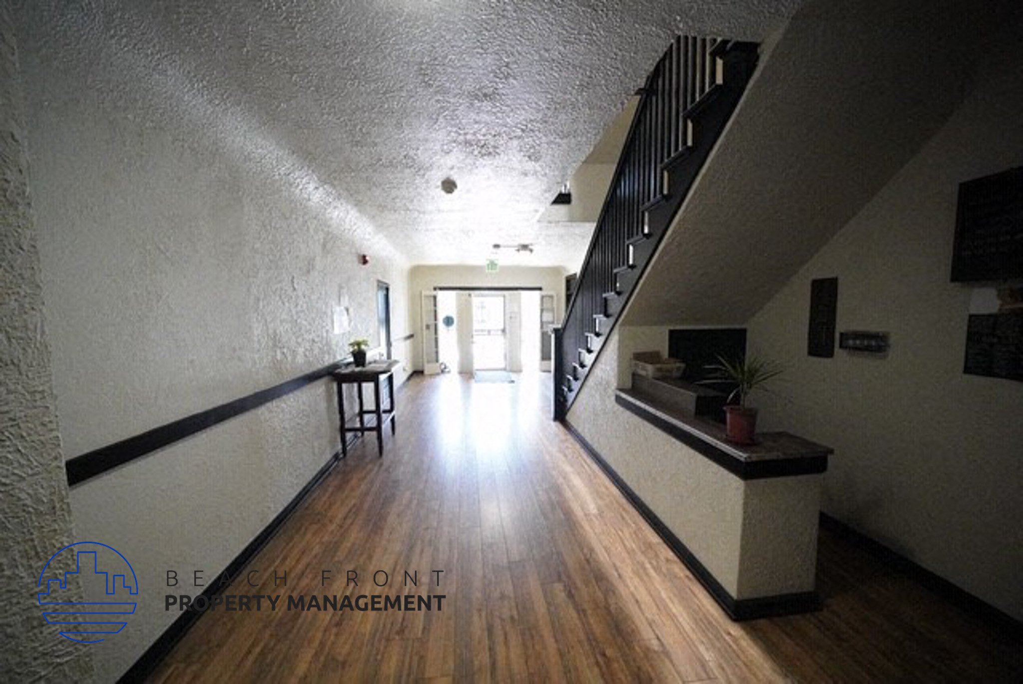 a hallway with a staircase and a hard wood floor