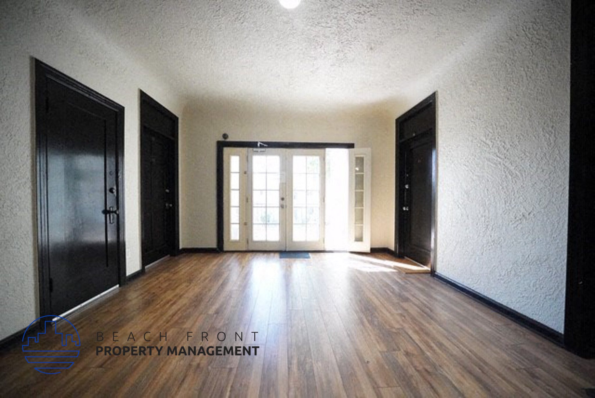 an empty living room with a wood floor and doors