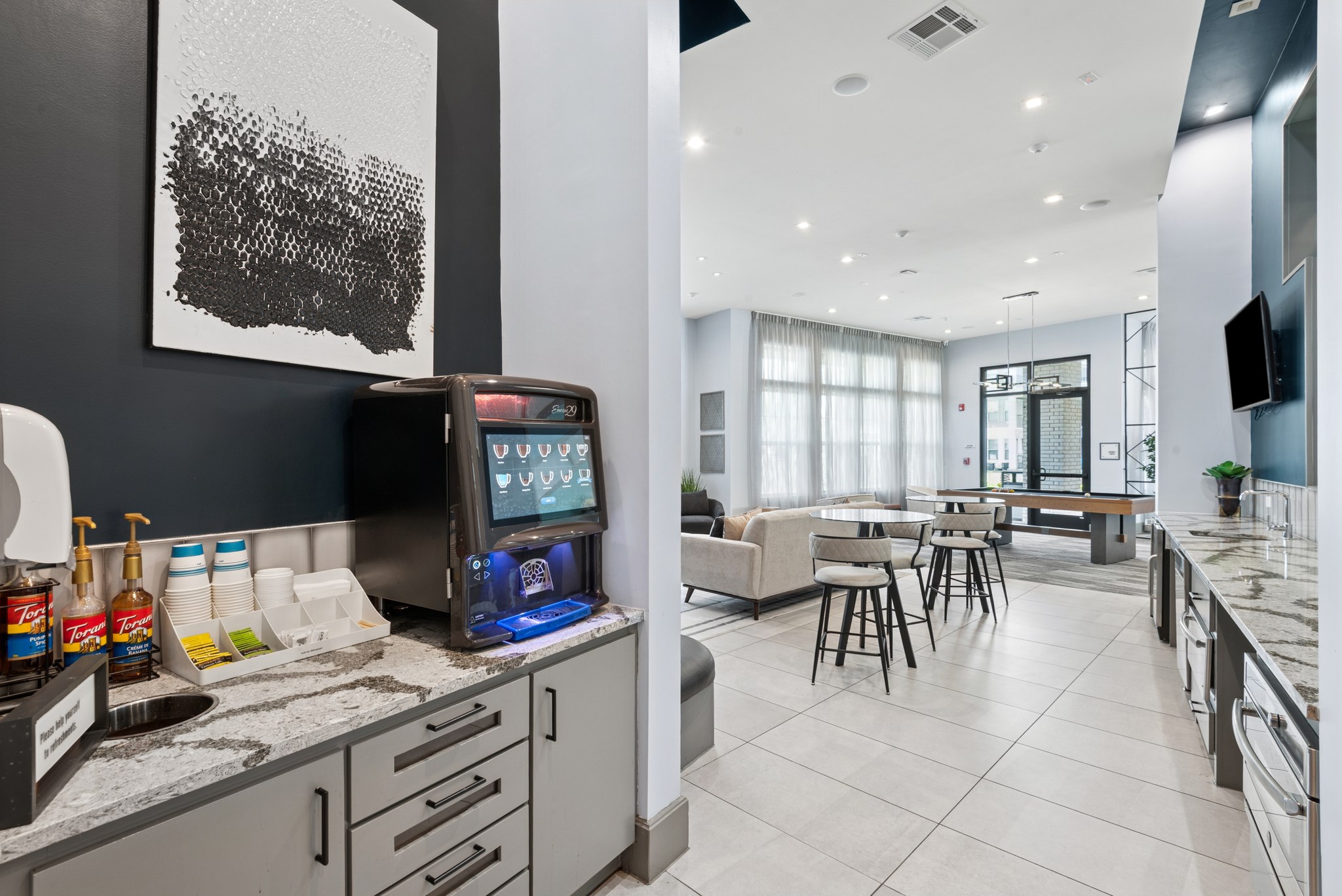 A modern kitchen with a black and white artwork on the wall.
