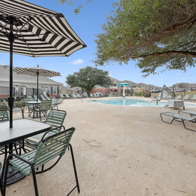 A patio with a table and chairs under an umbrella.