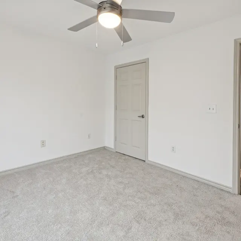 A room with a ceiling fan and carpeted floor.