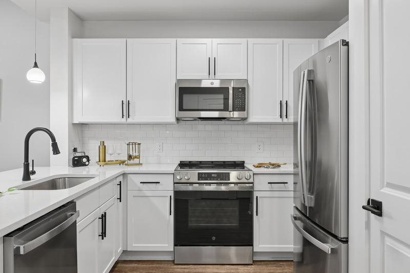 A modern kitchen with white cabinets and stainless steel appliances.