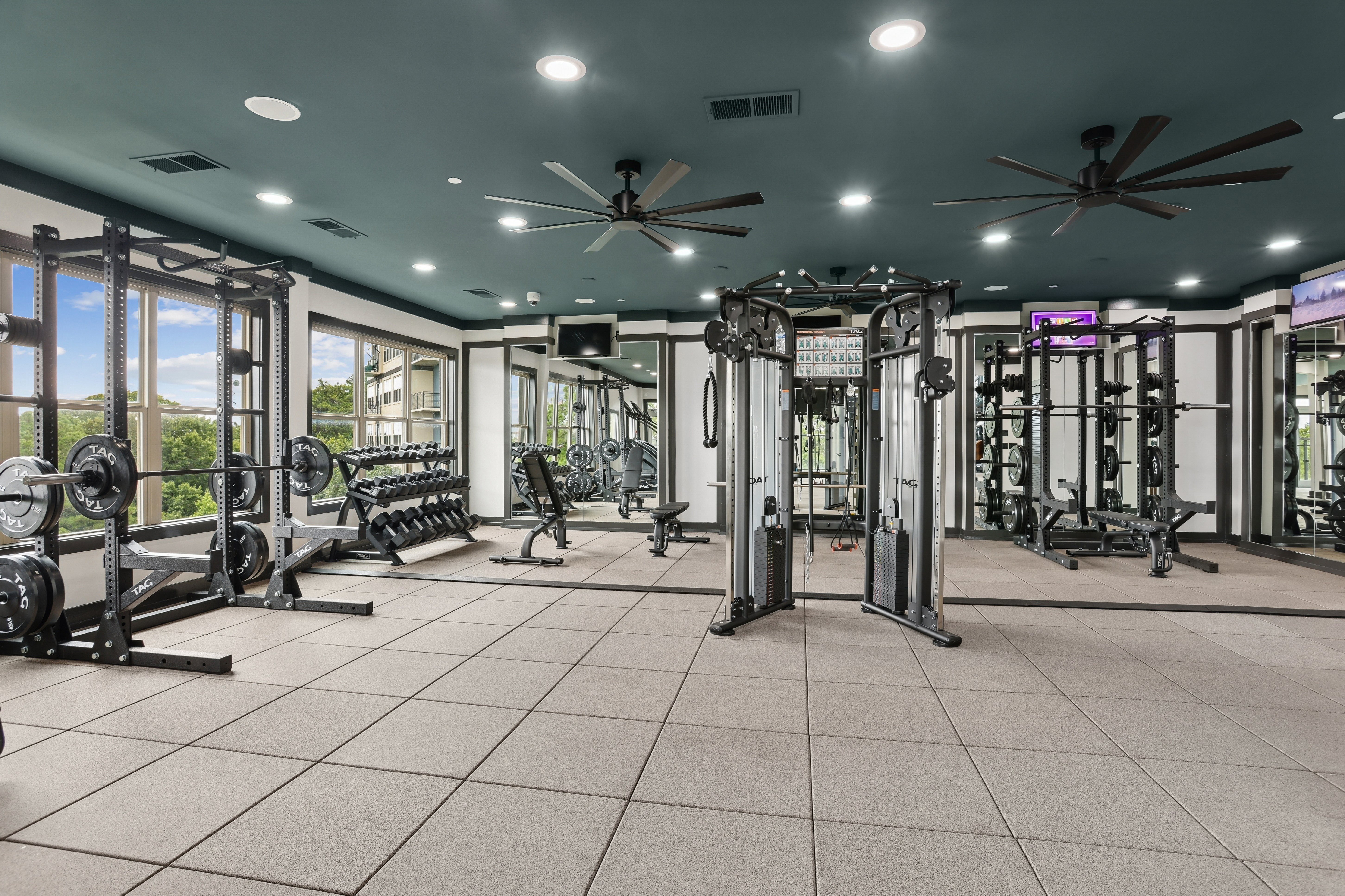 A spacious gym with a variety of equipment and a ceiling fan.