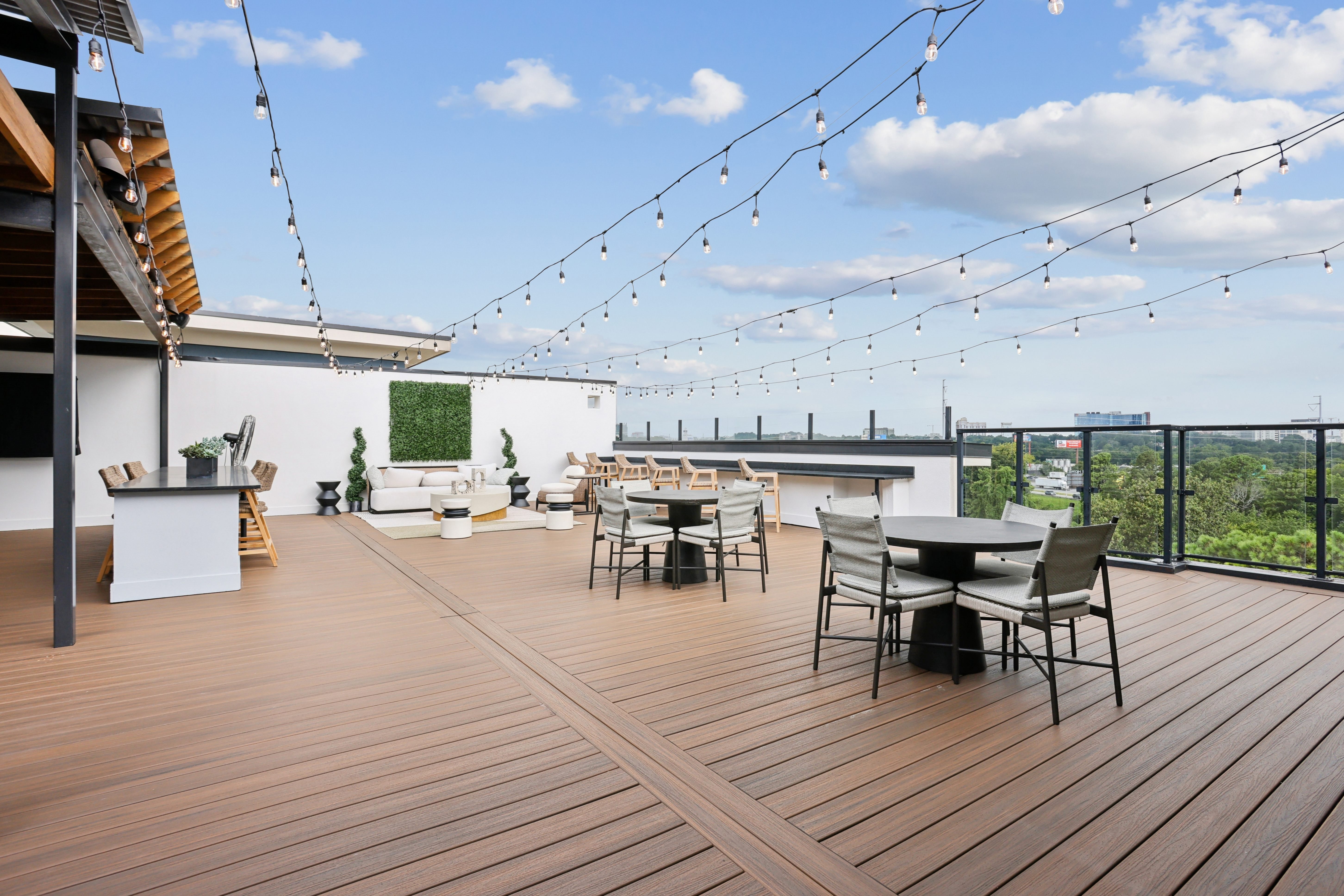 A wooden deck with a table and chairs is set up on a balcony.