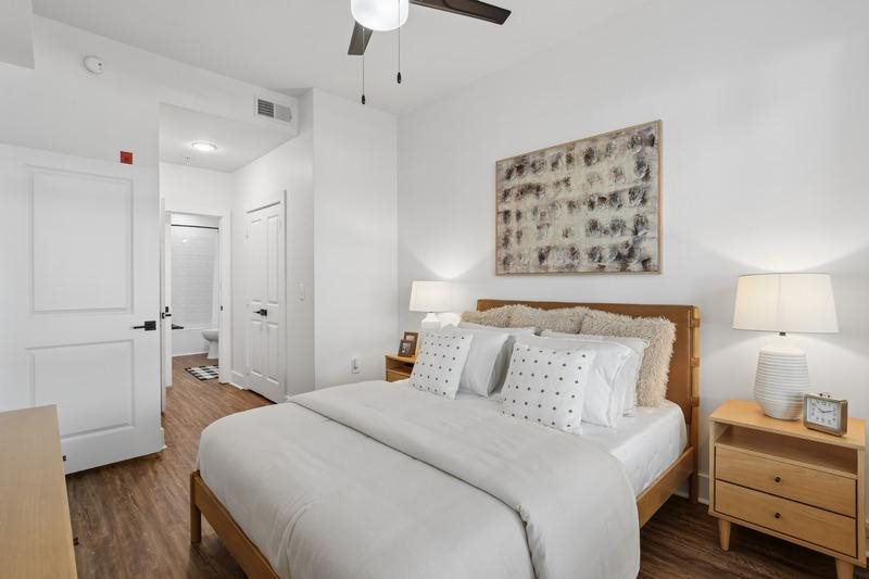 A bedroom with a large bed, a nightstand, and a ceiling fan.