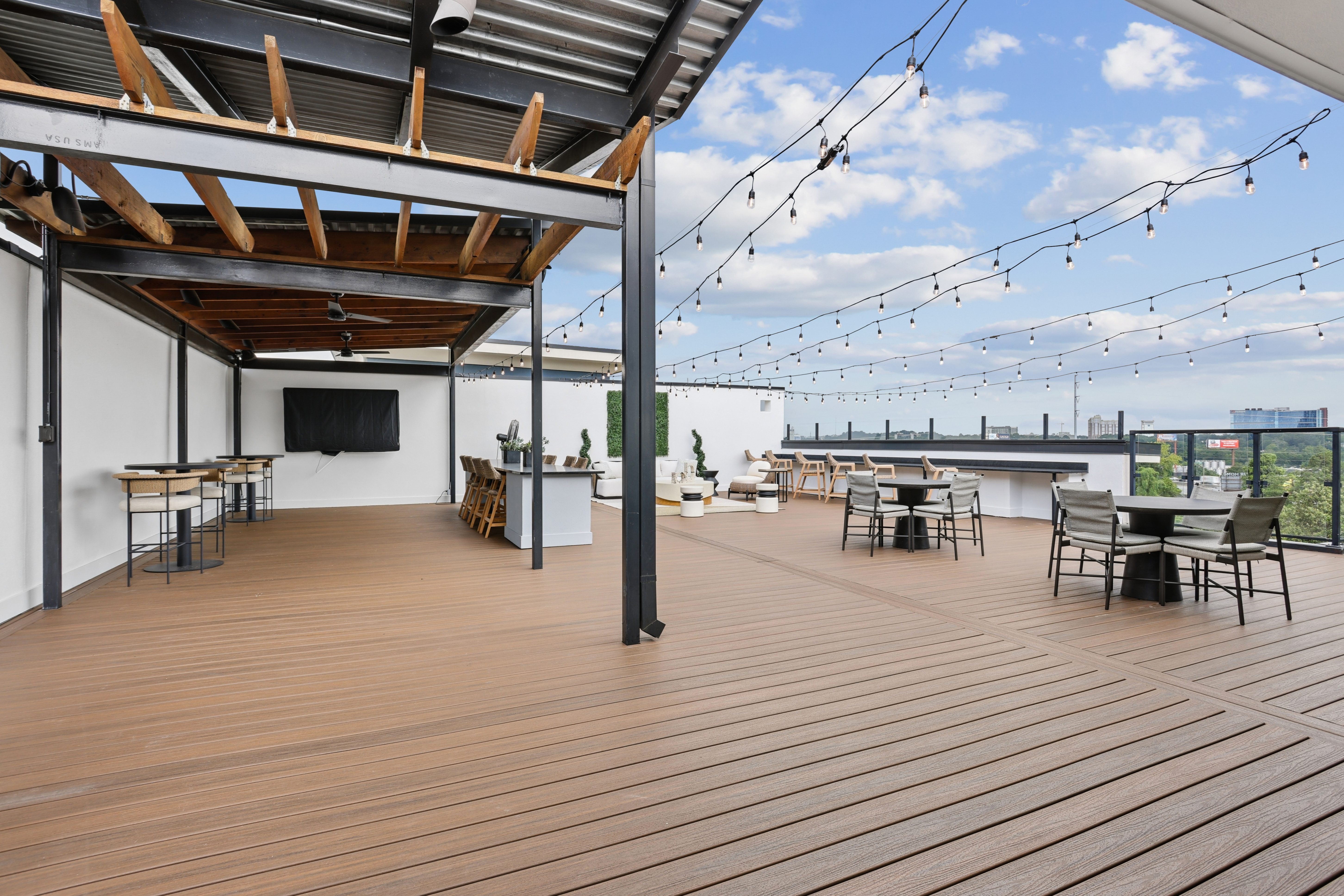 A wooden deck with tables and chairs and string lights.