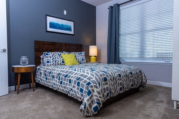 A bedroom with a bed, nightstand, and a painting on the wall.